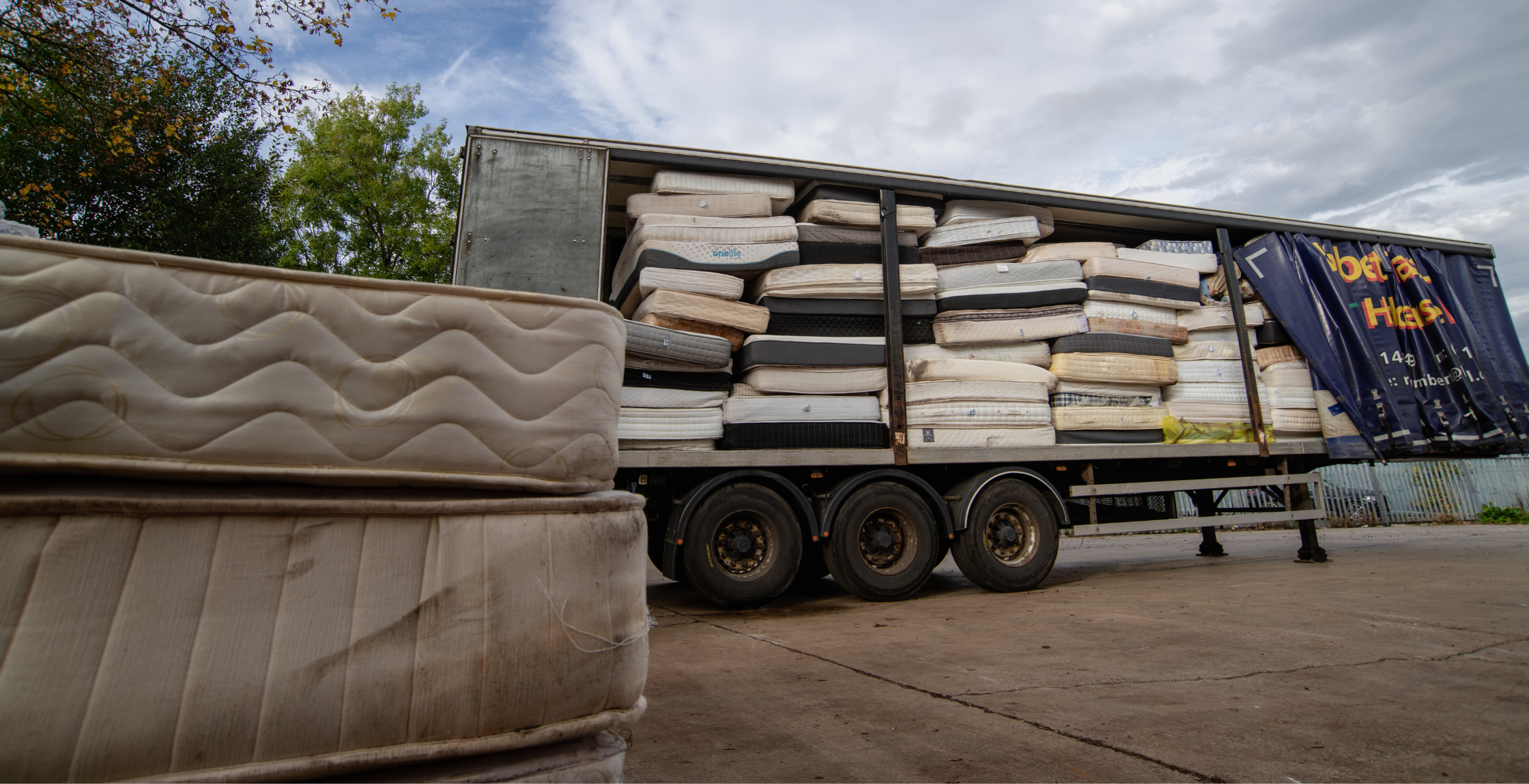 wagon trailer stood without the cab. The side is open, showing it completely full to the roof with used mattresses.